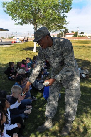 NELLIS AIR FORCE BASE, Nev.-- Senior Airman Marquis Hines, 99th Civil Engineer Squadron, hands out stickers to first graders from Lomie Heard Elementary School while teaching fire safety and describing the job of a Firefighter during the April 12 Career Event. The Career Event is a three day event where all Lomie Heard students get a chance to see multiple career paths available in and out of the military. (U.S. Air Force photo by Staff Sgt. Taylor Worley)