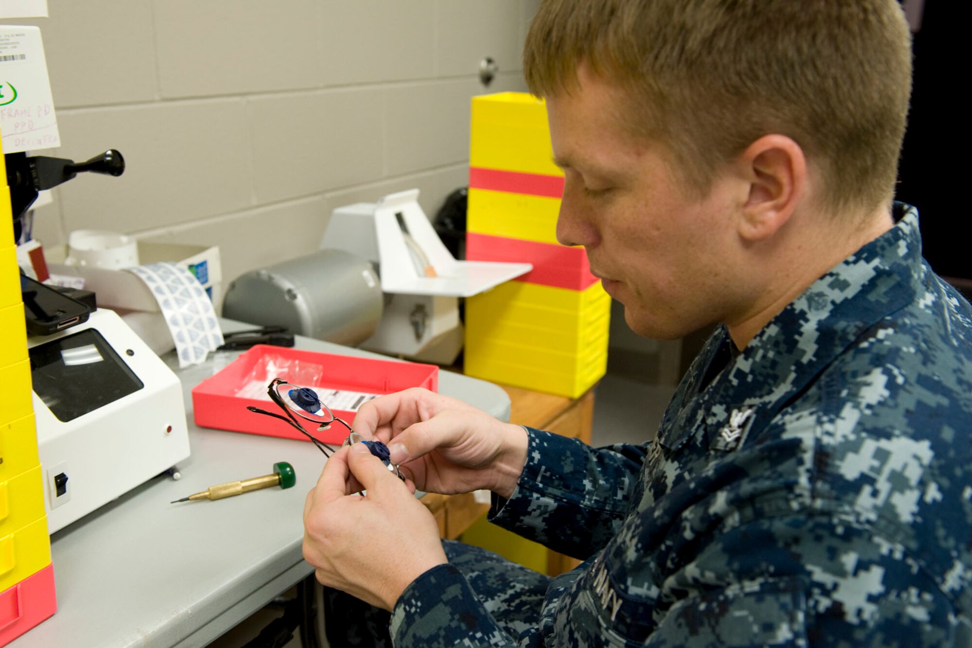 HAYNEVILLE, Ala. - U.S. Navy Petty Officer 2nd Class Phillip Cowger, an optician stationed at Naval Air Station Pensacola, Fla. places lenses into frames, May 5, 2011. The eyeglasses were a part of the optometry services offered under the Innovative Readiness Training (IRT) mission. The IRT program allows for real-world training opportunities for military personnel while providing needed services to under-served communities in the United States. There were about 70 deployers from numerous military components and services in Hayneville for the IRT mission.  Alaska Air National Guard photo by Master Sgt. Shannon Oleson.