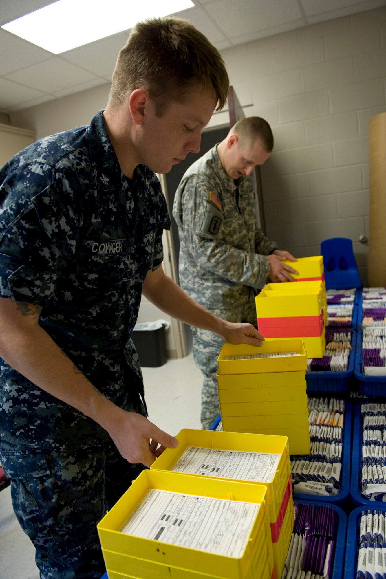 HAYNEVILLE, Ala. - U.S. Navy Petty Officer 2nd Class Phillip Cowger, an optician stationed at Naval Air Station Pensacola, Fla. and U.S. Army Spc. Louis Reuter III, an optical lab specialist stationed at Fort Eustis, Va., collect lenses to be used  for eyeglasses that will be given out for free, May 5, 2011. The eyeglasses were a part of the optometry services offered under the Innovative Readiness Training (IRT) mission. The IRT program allows for real-world training opportunities for military personnel while providing needed services to under-served communities in the United States. There were about 70 deployers from numerous military components and services in Hayneville for the IRT mission.  Alaska Air National Guard photo by Master Sgt. Shannon Oleson.