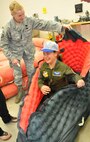 YOUNGSTOWN AIR RESERVE STATION, Ohio—Air Force Reserve Master Sgt. Cindy Cox, a Life Support Equipment Technician with the 910th Airlift Wing, helps 11 year-old Ashley Moorhead of Warren, climb into a life raft during her visit to the life support repair shop.  Ashley was sworn in as an honorary Air Force Reserve 2nd Lieutenant and Pilot for a Day May 4, 2011, when she visited the air station for an exciting schedule of events. Ashley is currently receiving treatment for Cerebral Palsy at Akron Children's Hospital Mahoning Valley. The purpose of the Pilot for a Day program is to reach out to the community by providing a fun-filled day of activities to children who live with a chronic or life-threatening disease or illness. The Youngstown Air Reserve Station Base-Community Council is the financial co-sponsor of the program.  As part of the program, children are selected to visit the base, receive a genuine aircrew flight suit and other mementos as well as receive an enlightening tour of the base.  Included as part of the tour are a visit to the Life Support shop, firing the Fire Arms Training Simulator, a ride on a base fire truck and being taxied aboard a million C-130 Hercules aircraft down the runway.  U.S. Air Force photo by Maj. Brent Davis 
