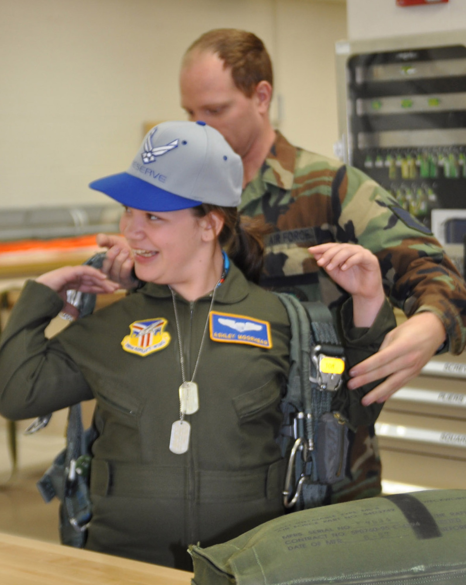 YOUNGSTOWN AIR RESERVE STATION, Ohio —Air Force Reserve Tech. Sgt. Joel Barton, a Life Support Equipment Technician with the 910th Airlift Wing, helps 11 year-old Ashley Moorhead of Warren, don a parachute during her visit to the life support equipment repair shop.  Ashley was sworn in as an honorary Air Force Reserve 2nd Lieutenant and Pilot for a Day May 4, 2011, when she visited the air station for an exciting schedule of events. Ashley is currently receiving treatment for Cerebral Palsy at Akron Children's Hospital Mahoning Valley. The purpose of the Pilot for a Day program is to reach out to the community by providing a fun-filled day of activities to children who live with a chronic or life-threatening disease or illness. 
The Youngstown Air Reserve Station Base-Community Council is the financial co-sponsor of the program.  As part of the program, children are selected to visit the base, receive a genuine aircrew flight suit and other mementos as well as receive an enlightening tour of the base.  Included as part of the tour are a visit to the Life Support shop, firing the Fire Arms Training Simulator, a ride on a base fire truck and being taxied aboard a million C-130 Hercules aircraft down the runway.  U.S. Air Force photo by Maj. Brent Davis
