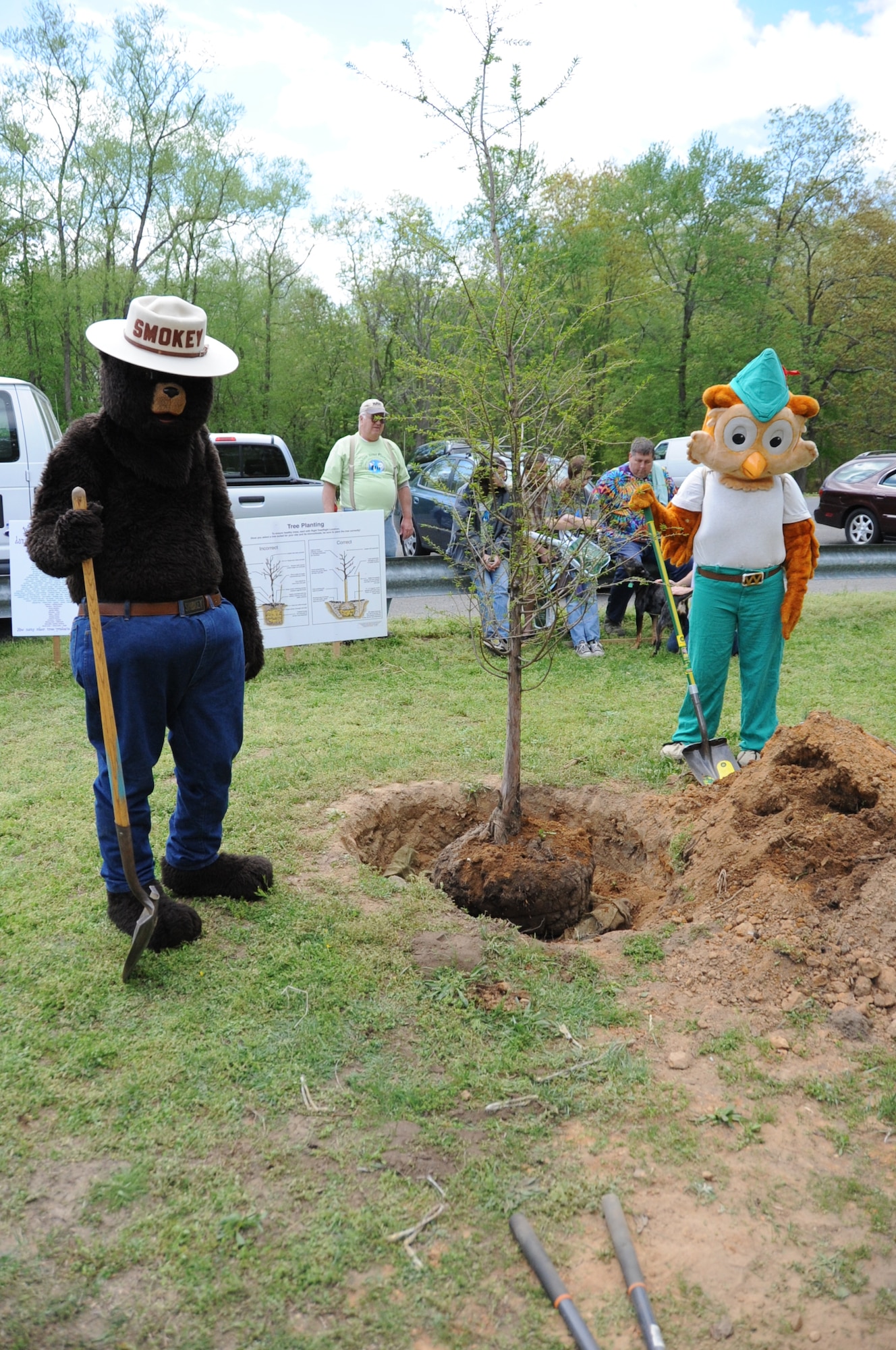 Smoky the Bear and Woodsy the Owl toss pile of dirt on the newly-planted tree during the Joint Base McGuire-Dix-Lakehurst Earth Day celebration Saturday at Laurel Pond. More than 500 community members attended the 6-hour event which included a puppet show, canoeing, tree climbing, a pollination station and static displays from local nature centers and parks. (U.S. Air Force photo by Airman 1st Class Bryan Swink/Released)