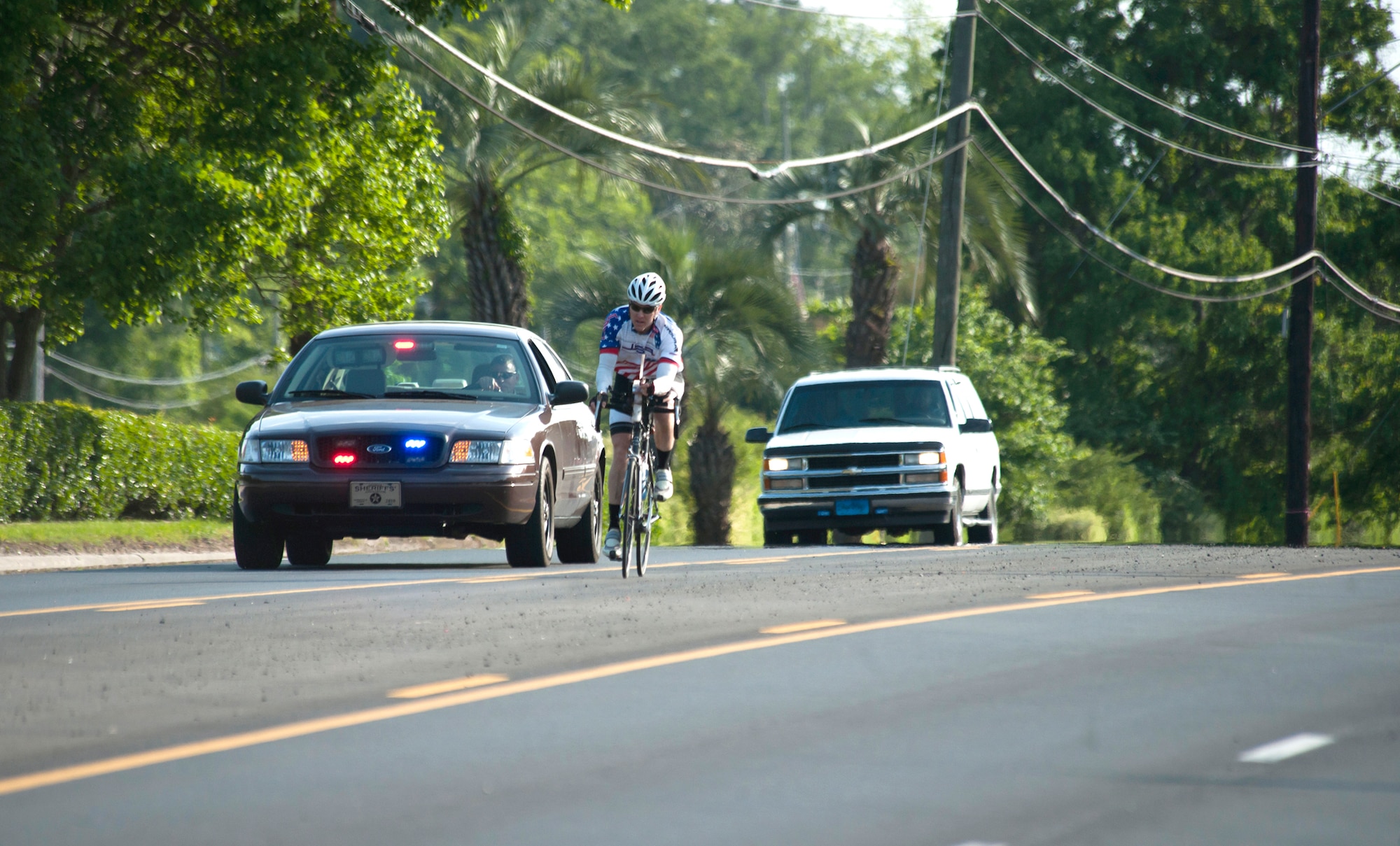 Jason Rogers, an Air Force veteran, rides his bicycle May 2, 2011, in Waycross, Ga., on the final stretch of his journey to meet a crowd of friends and family. Mr. Rogers had two police car escorts to lead him to the finish. (U.S. Air Force photo/Airman 1st Class Jarrod Grammel)