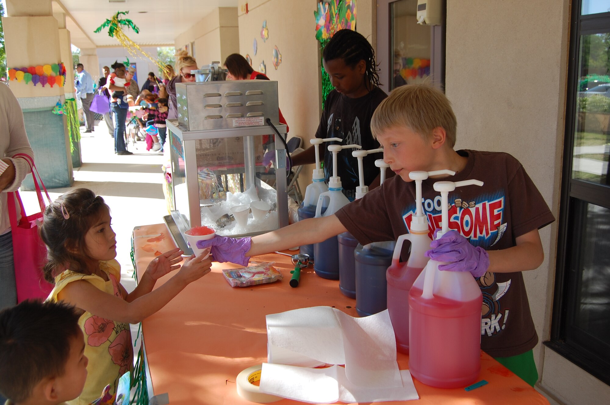 Josh McCracken, right, hands Novelly Zavala a watermelon-flavored snowcone while Dominic Davies, second from right, prepares one for Novelly’s brother.