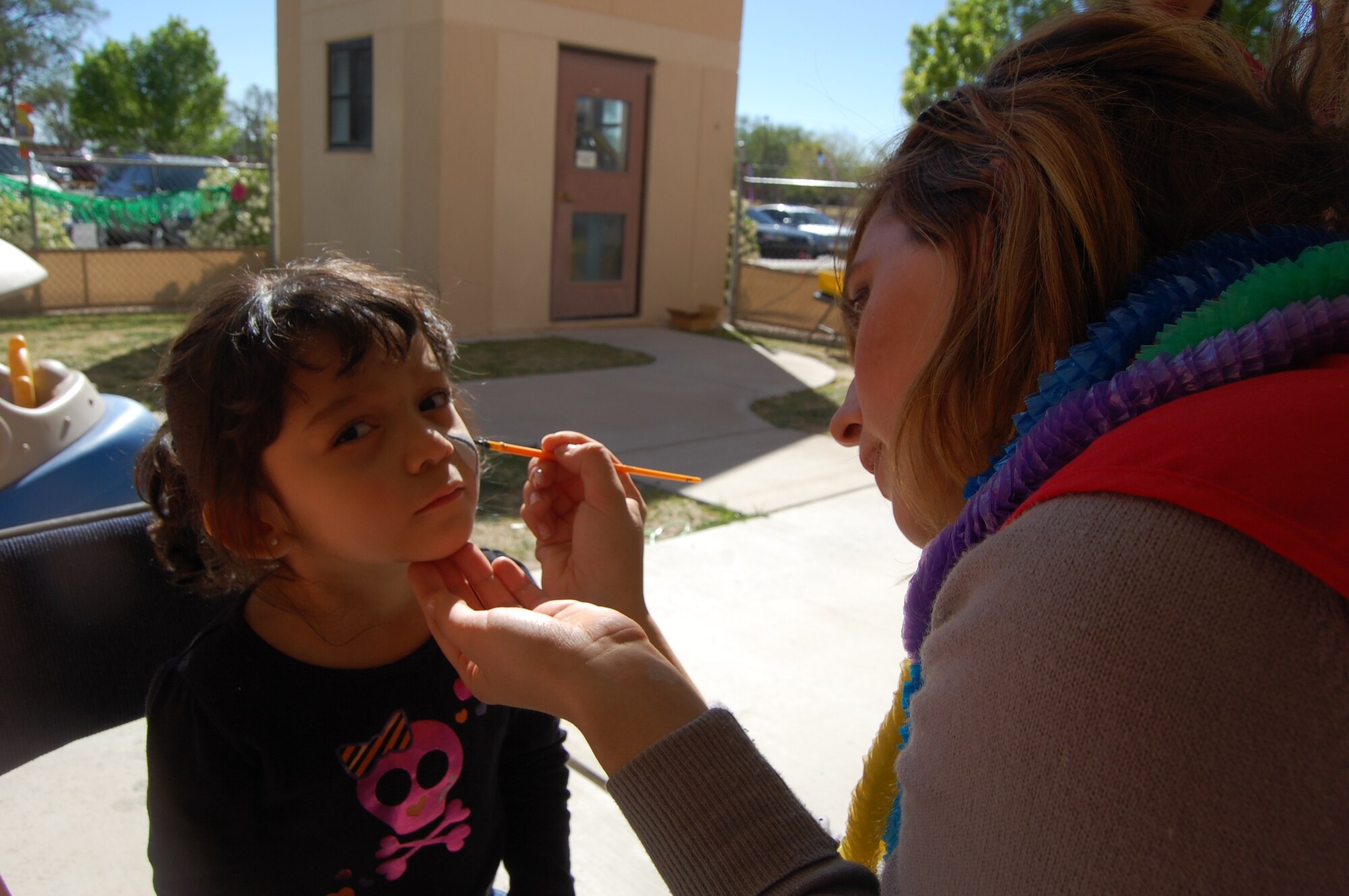 Mary Moore, right, paints a cat’s face on Alana LeBlanc’s cheek.