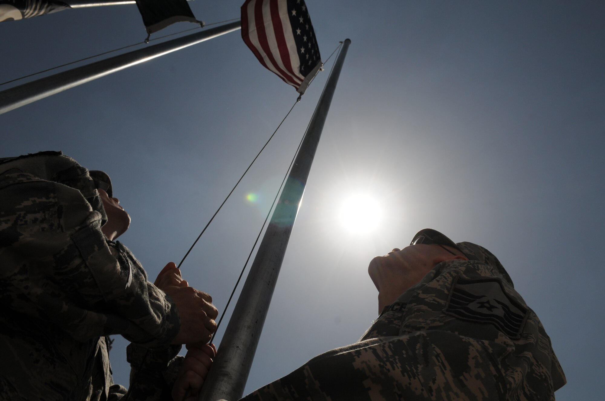KABUL, Afghanistan -- Two Airmen raise the U.S. flag during a flag-raising ceremony at the 438th Air Expeditionary Wing May 6. The ceremony marked nine days to the hour when eight Airmen and one retired Army civilian contractor were killed when a gunman opened fire during a meeting with NATO trainers.  (U.S. Air Force photo by Tech. Sgt. Brian E. Christiansen)