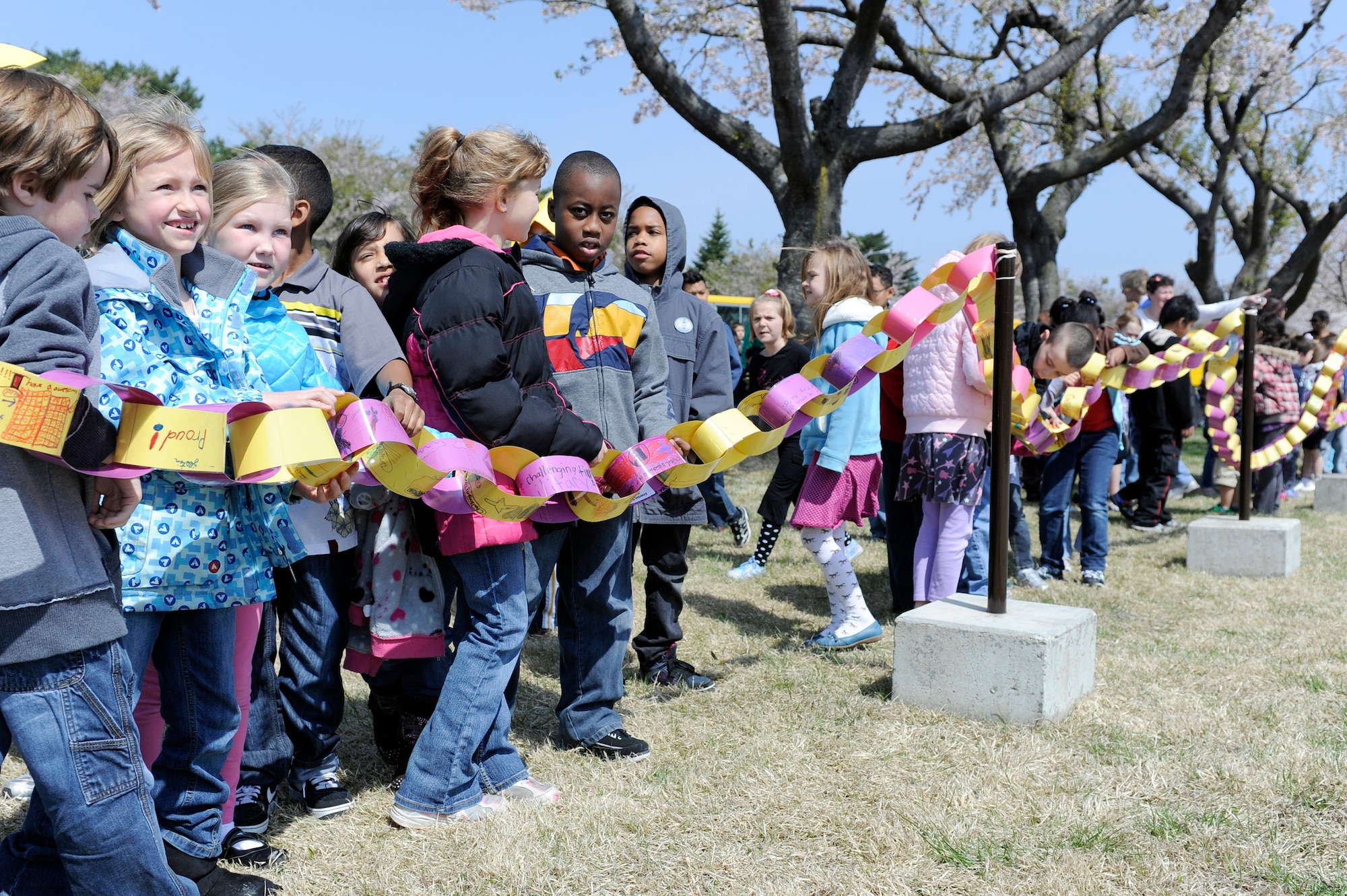 MISAWA AIR BASE, Japan -- Approximately 165 students line up behind a paper link chain at the base flag pole May 6. The paper chain was made in hopes of inspiring student's creativity while inviting them to bridge the gap between themselves and other military families living here at Misawa. (U.S. Air Force photo/Staff Sgt. Marie Brown/Released)