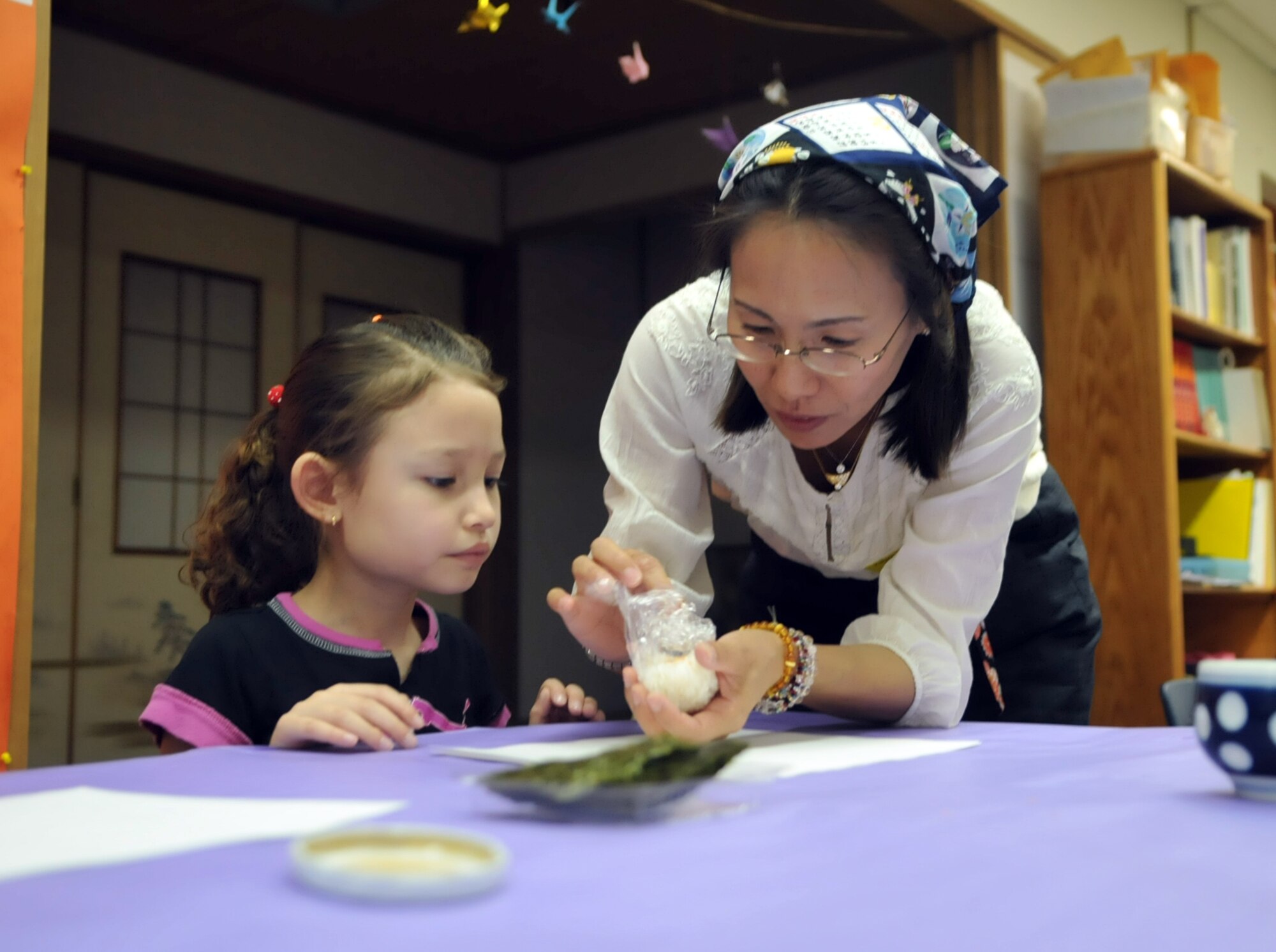 YOKOTA AIR BASE, Japan -- Naoko Tanoue, a multicultural event volunteer, helps Julie Ibarra, 1st grade student at Yokota West Elementary School, with making a rice ball at Yokota Air Base, Japan, May 5, 2011. Students made onigiri, also known as rice balls, in celebration of Japanese tradition. (U.S. Air Force photo/Airman Krystal M. Garrett) 