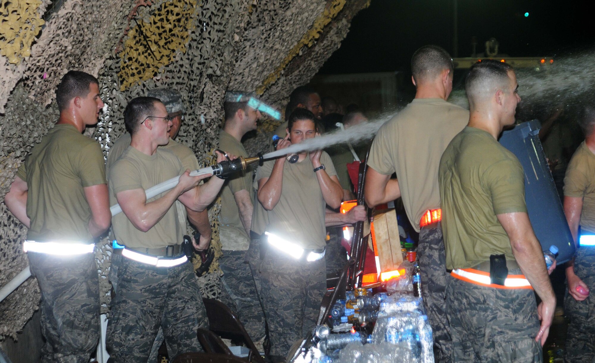 Airmen from the 379 Expeditionary Civil Engineer Squadron spray the crowd during a Combat Dining In event 4 May in Southwest Asia. Many Airmen from the ECES participated in the evenings events. (U.S. Air Force photo/ Staff Sgt. Anthony Graham)