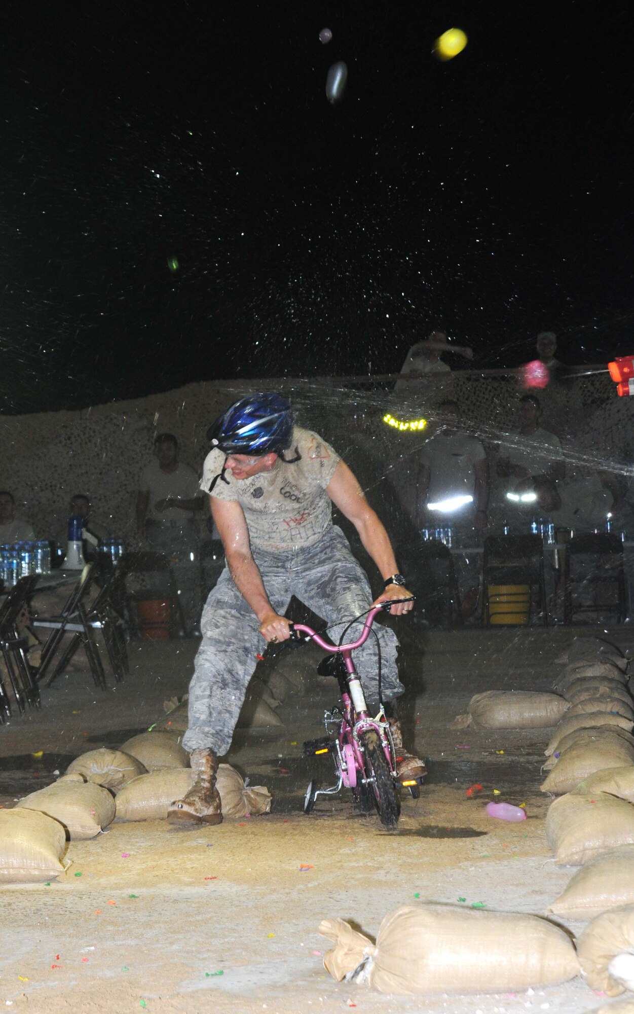 Capt. Aaron Cooper from the 379 Expeditionary Civil Engineer Squadron attempts to ride a tricycle while being sprayed with water during a Combat Dining In event 4 May in Southwest Asia. The event contained many different events throughout the night.(U.S. Air Force photo/ Staff Sgt. Anthony Graham)