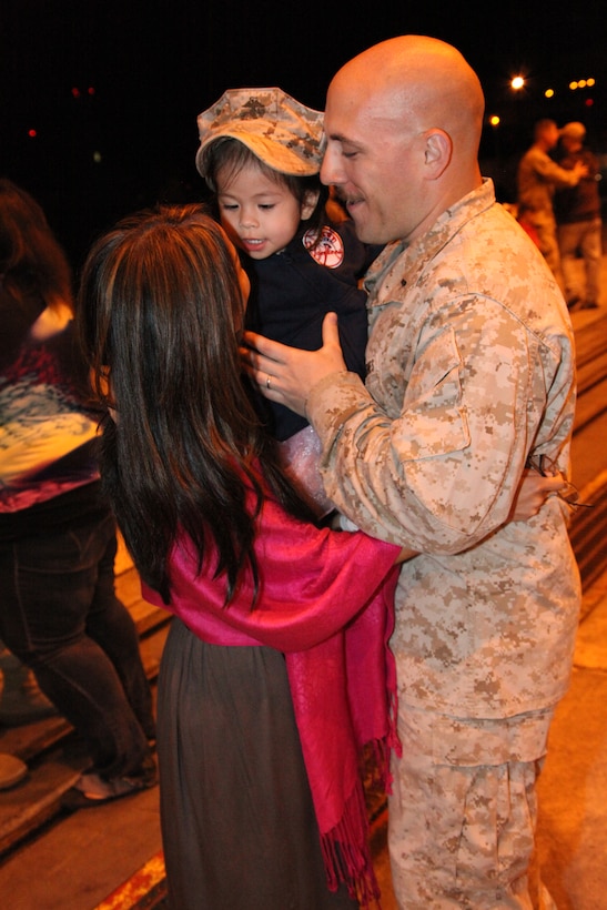 1st Lt. Christopher J. DiNoto, his wife Trinh, and their daughter, Claire, share a special moment at the return of Marine Tactical Electronic Warfare Squadron 3 to Cherry Point May 7. DiNoto, an intelligence officer for VMAQ-3, returned home from a six-month deployment where the squadron flew more than 630 missions in support of operations in Afghanistan.