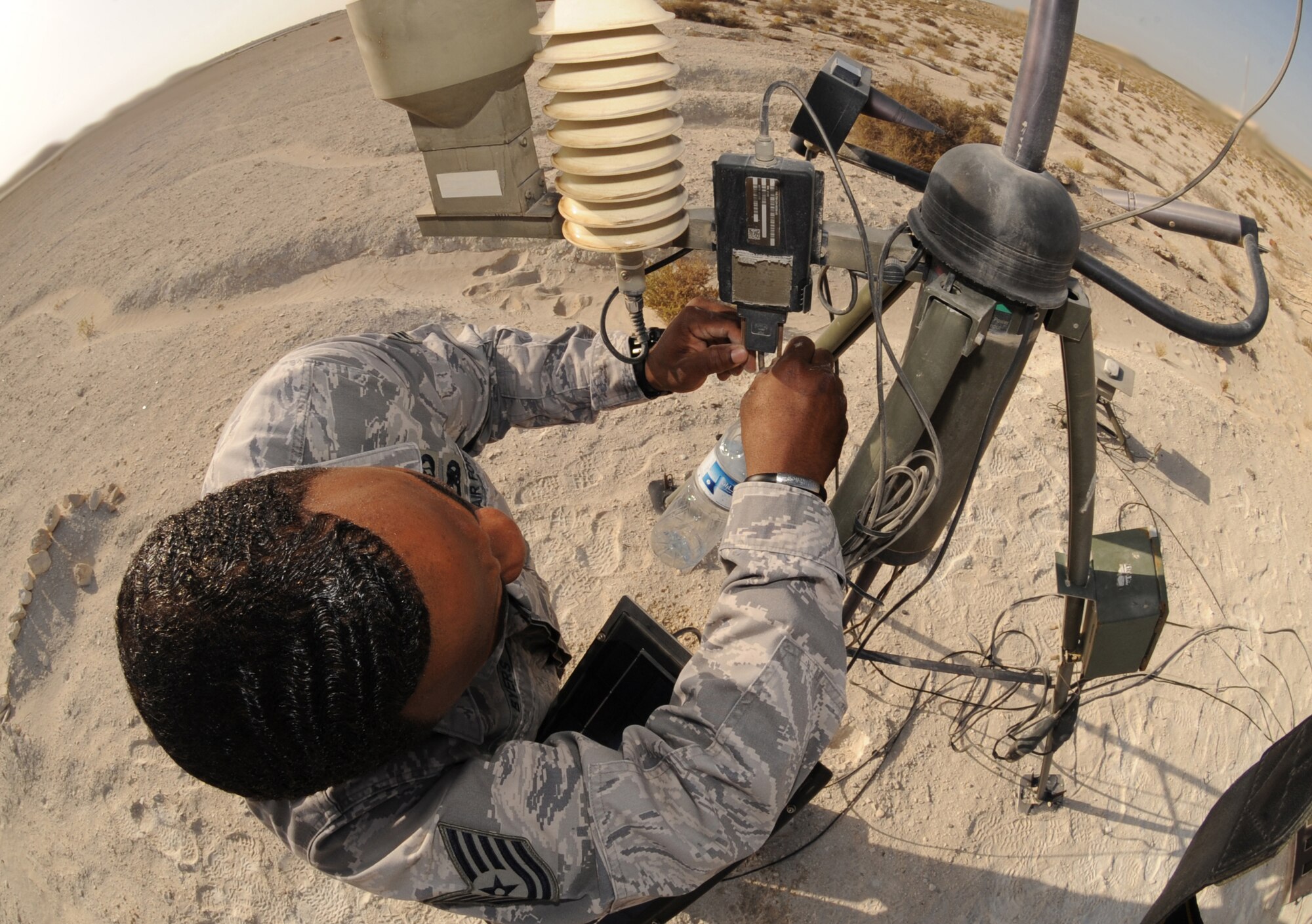Tech. Sgt. Shannon Byers, 380th Expeditionary Operations Support Squadron, ensures the connections on an AN/TMQ-53 Tactical Meteorological Observing System are secure and show no signs of galling or corrosion during a preventative maintenance inspection. These systems use the Iridium network of 66 low-earth orbiting satellites to provide near-real-time mission-critical weather data to war planners and decision makers. (U.S. Air Force photo by Senior Airman Maynelinne De La Cruz)