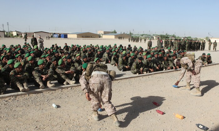 Two Marines with 2nd Combat Engineer Battalion, 2nd Marine Division (Forward) use painted water bottles representing each member in the formation, to demonstrate the different ways to scan the ground for Improvised Explosive Devices and mines during an awareness class May 9, 2011, aboard Camp Shorabak, Afghanistan.  Nearly 160 Afghan National Army soldiers with the 215th Corps Logistics Battalion attended the period of instruction to prepare for future mission across Helmand province.