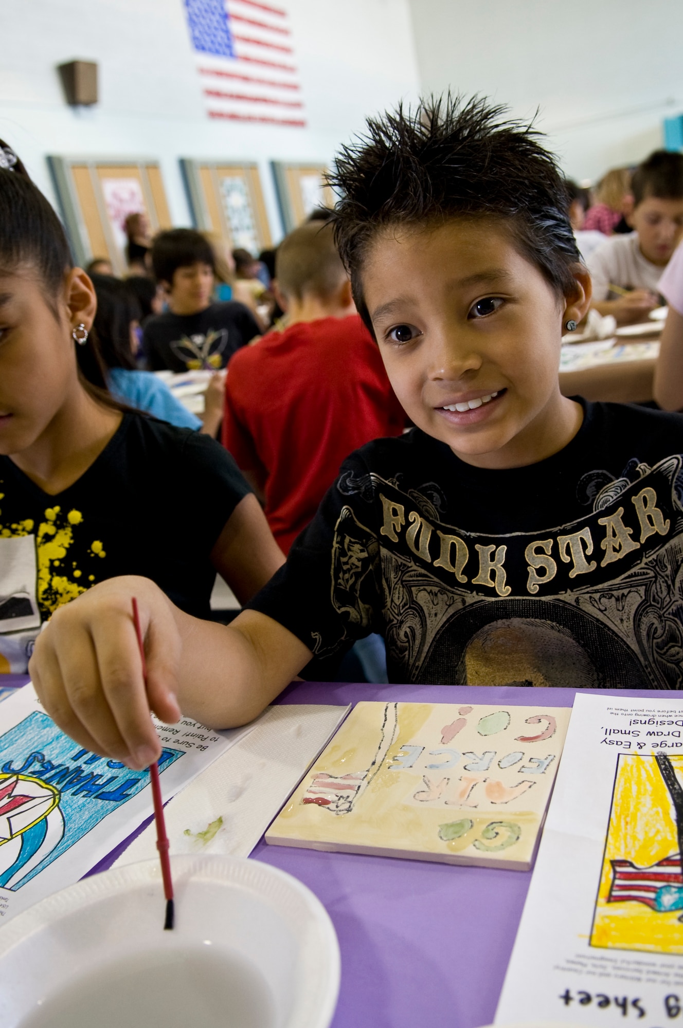 NELLIS AIR FORCE BASE, Nev. -- Liam Hurtado Carol, Lomie Heard Elementary School student and son of Staff Sgt. Iliana Hurtado, 99th Logistics Readiness Squadron Flight Service Center non-commissioned officer in charge, rinses his paintbrush off after painting on a ceramic tile May 5. More than 125 students were chosen to paint pictures on the tiles for a mural that will be displayed in the USO common room at the McCarran International Airport, Las Vegas. (U.S. Air Force photo by Airman 1st Class George Goslin)

