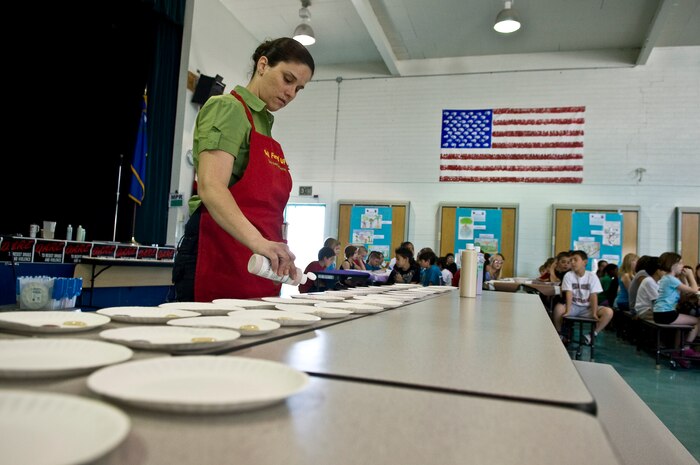 NELLIS AIR FORCE BASE, Nev. -- Sheryl Page, "All Fired Up" ceramic stdio assistant manager, fills paper plates with different colors of paint for the students to use on their tiles at Lomie Heard Elementary School, May 5. More than 125 students were chosen to paint pictures on the tiles for a mural that will be displayed in the USO common room at the McCarran International Airport, Las Vegas. (U.S. Air Force photo by Airman 1st Class George Goslin) 