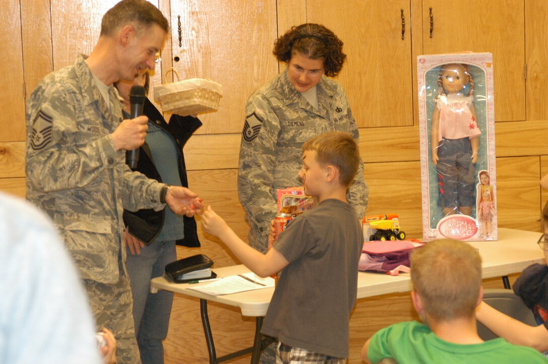 SMSgt Mike Woods and MSgt Sandra Tiemens give away door prizes to kids at the Peterson AFB Deployed Families Dinner, hosted by the USAF Academy Band. This lucky winner is the son of MSgt Karl Bradley, who is deployed in SW Asia with Wild Blue Country from the USAF Academy Band.