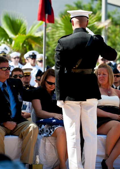 A Marine officer salutes the widow of a fallen explosive ordnance disposal technician after presenting an American Flag flown over the memorial during a ceremony May 7 at Eglin Air Force Base, Fla.  Fifteen new names were added to the memorial wall this year.  The total, which includes all services, now stands at 269.  The Marine Corps added eight names to the wall – Staff Sgts. Adam Perkins, Joshua Cullins, Jordan Emrick, Gunnery Sgt.s Christopher Eastman, Floyd Holley, Justin Schmalstieg, Master Sgt. Daniel Fedder and Sgt. Jason Smith. (U.S. Air Force photo/Samuel King Jr.)