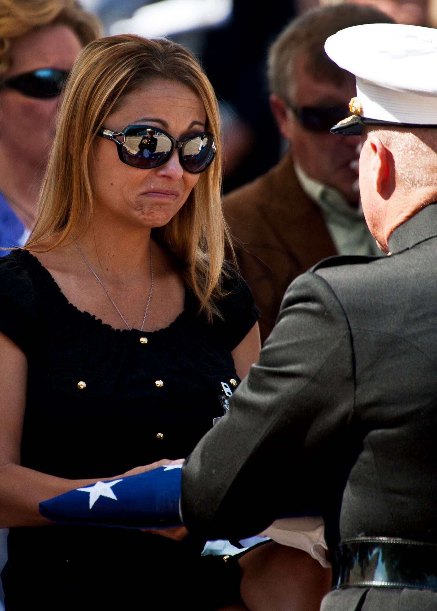 A Marine widow accepts an American Flag flown over the Explosive Ordnance Disposal memorial during the annual ceremony May 7 at Eglin Air Force Base, Fla.  Fifteen new names were added to the memorial wall this year.  The total, which includes all services, now stands at 269.  The Marine Corps added eight names to the wall – Staff Sgt.s Adam Perkins, Joshua Cullins, Jordan Emrick, Gunnery Sgt.s Christopher Eastman, Floyd Holley, Justin Schmalstieg, Master Sgt. Daniel Fedder and Sgt. Jason Smith. (U.S. Air Force photo/Samuel King Jr.)