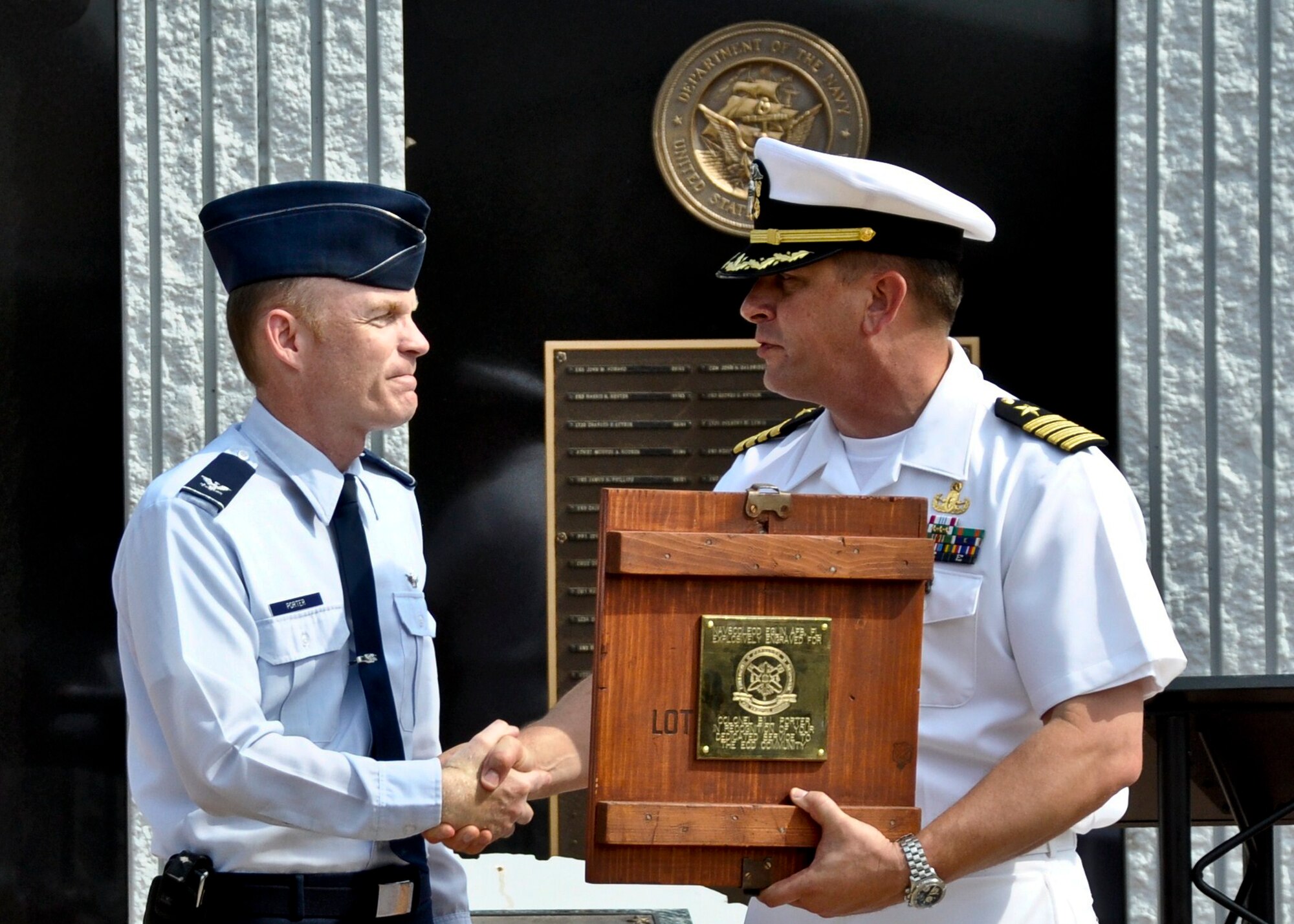 Col. Bill Porter, 96th Air Base Wing vice commander, accepts a plaque from the outgoing commander of the Naval School Explosive Ordnance Disposal, Capt. Adam Guziewicz, May 9. Captain Guziewicz expressed his appreciation to Colonel Porter personally for his assistance during the captain's command.  Commander Joseph Polanin  assumed command of the school from Captain Guziewicz, marking the 25th change of leadership since the school's establishment in 1941. (USAF photo/Lois Walsh)