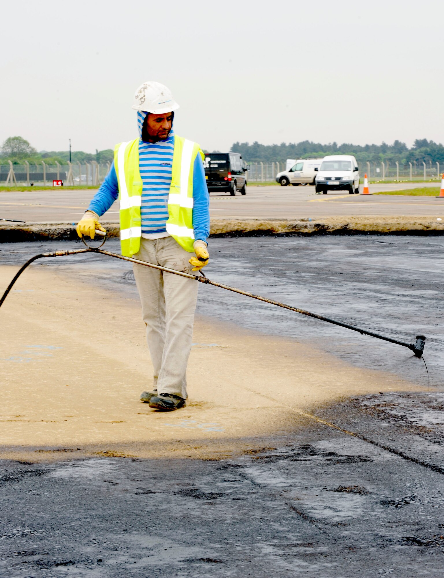 RAF MILDENHALL, England -- Balwinder Singh, a local contractor, sprays a K-140 Benjamin curing agent onto a lean mix concrete base on an airfield pavement (hardstand) here May 5, 2011. The curing agent is sprayed to prevent it from drying and cracking before the second layer of the foundation is put into place. (U.S. Air Force photo/Senior Airman Ethan Morgan)