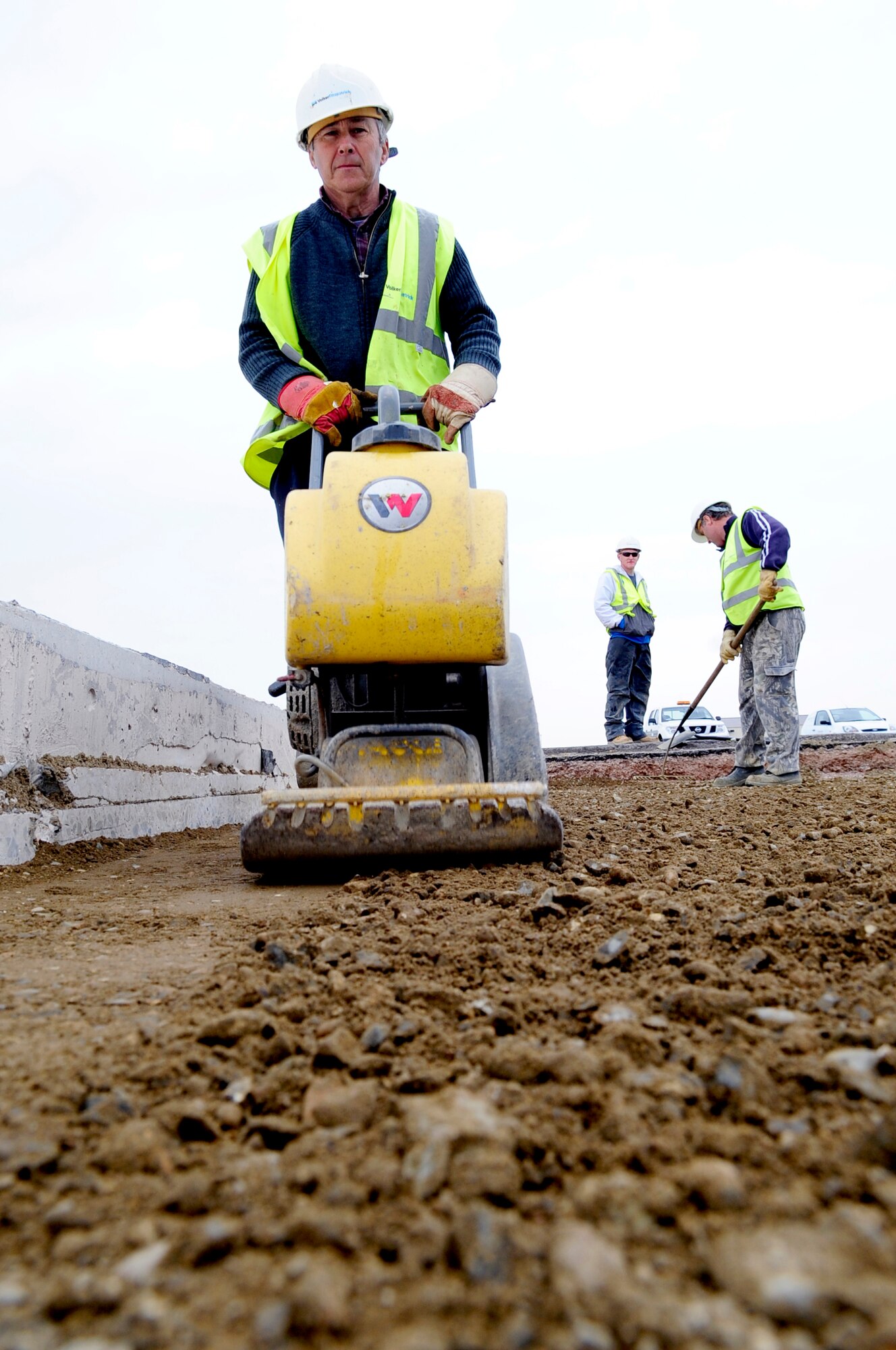 RAF MILDENHALL, England -- Peter Kent, a local contractor, uses a mobile compactor to pack and flatten a lean mix concrete base for an airfield pavement (hardstand) repair here May 5, 2011.  The hardstands are undergoing an upgrade project that will renew them after 20 years of use. (U.S. Air Force photo/Senior Airman Ethan Morgan)
