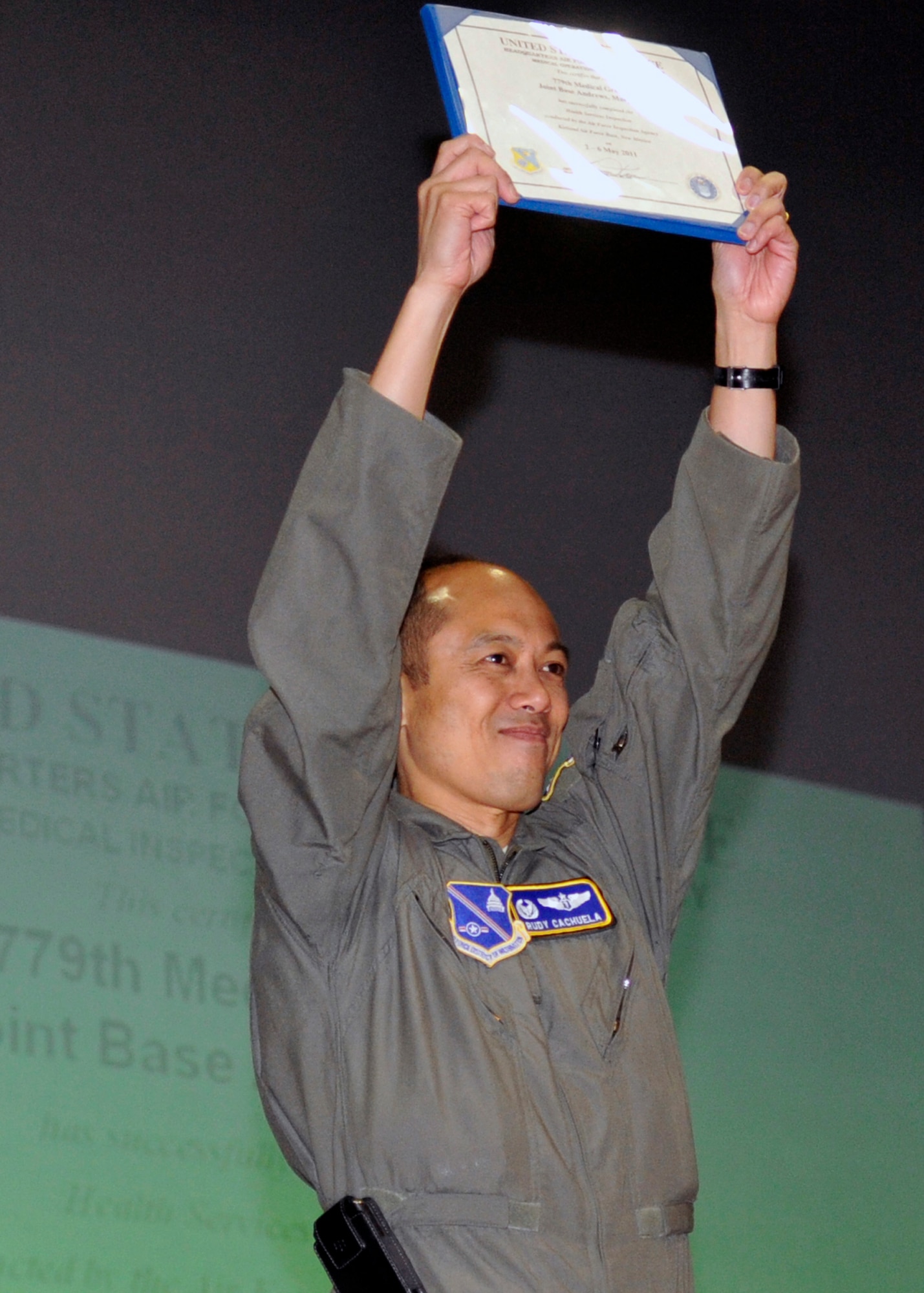 779th Medical Group commander, Colonel Rudolph Cachuela, proudly holds up the graduation certificate from the Inspector General team during an outbrief Friday, May 6. The document certifies that the 779 MDG received an "Outstanding" result on the Health Services Inspection. (U.S. Air Force photo/Senior Airman Laura Turner)