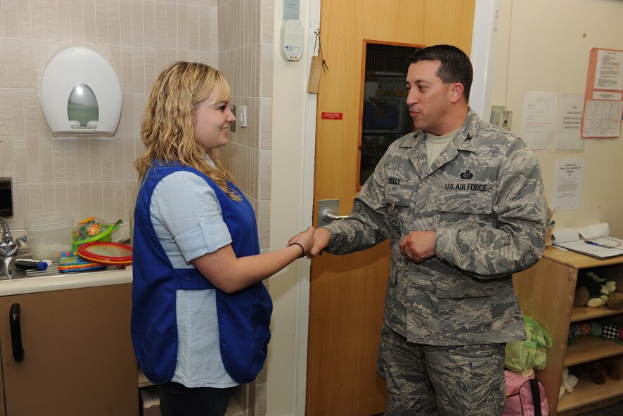 Col. Brian Kelly presents a coin to Natasha Matthews at the RAF Alconbury Child Development Center May 6, in recognition of her volunteering to support the Aviano CDC during Operations Odyssey Dawn and Unified Protector. (U.S. Air Force photo by Tech. Sgt. John Barton) 