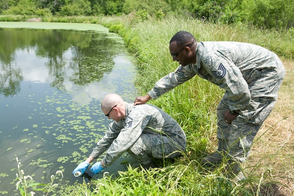 HAYNEVILLE, Ala. - Master Sgt. Ryan Voigt, a a bioenvironmental engineering technician with the 176th Medical Group, Alaska Air National Guard, collects a sample of water from the City of Hayneville?s waste-water treatment lagoon while Tech. Sgt. Dainard Caldwell, a public health technician with group, holds onto him to keep him from falling into the lagoon, May 8, 2011.  Voigt and Caldwell were in Alabama to help test the waste water for permit compliance and related treatment adjustments, and with drinking water for chlorine amount. They were also deploy with another seventy servicemembers from numerous military components and services in Hayneville for an Innovative Readiness Training (IRT) mission. The IRT program allows for real world training opportunities for military personnel while providing needed services to under-served communities in the United States. Alaska Air National Guard photo by Master Sgt. Shannon Oleson.