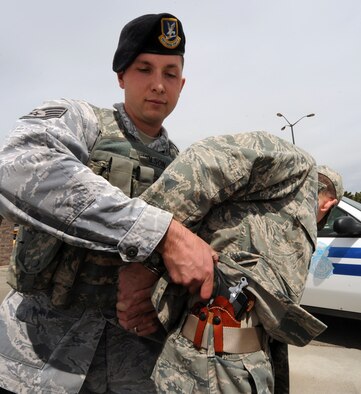 MOUNTAIN HOME AIR FORCE BASE, Idaho – Staff Sergeant Robert Wilson, 366th Security Forces Squadron Military working dog handler, demonstrates taking custody of an illegally concealed weapon discovered during a search at the main gate here. State-issued concealed carry permits are not valid on base, and all concealed carry is prohibited on the installation. (U.S. Air Force photo by Senior Airman Debbie Lockhart) 

