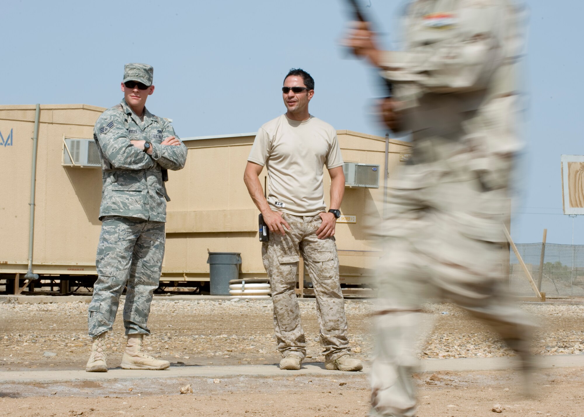 ALI AIR BASE, Iraq -- Senior Airman Chris Kelly, left, and a linguist, 407th Expeditionary Security Forces Squadron members, watch Iraqi security forces students demonstrate force protection measures April 19. The class, the fourth one conducted during the past three months, was to familiarize Iraqi air force members with force protection measures in order to protect their own assets when U.S. forces transition out. Airman Kelly is deployed from Lackland Air Force Base, Texas, and is a native of Pensacola, Fla. (U.S. Air Force photo by Staff Sgt. Levi Riendeau)
