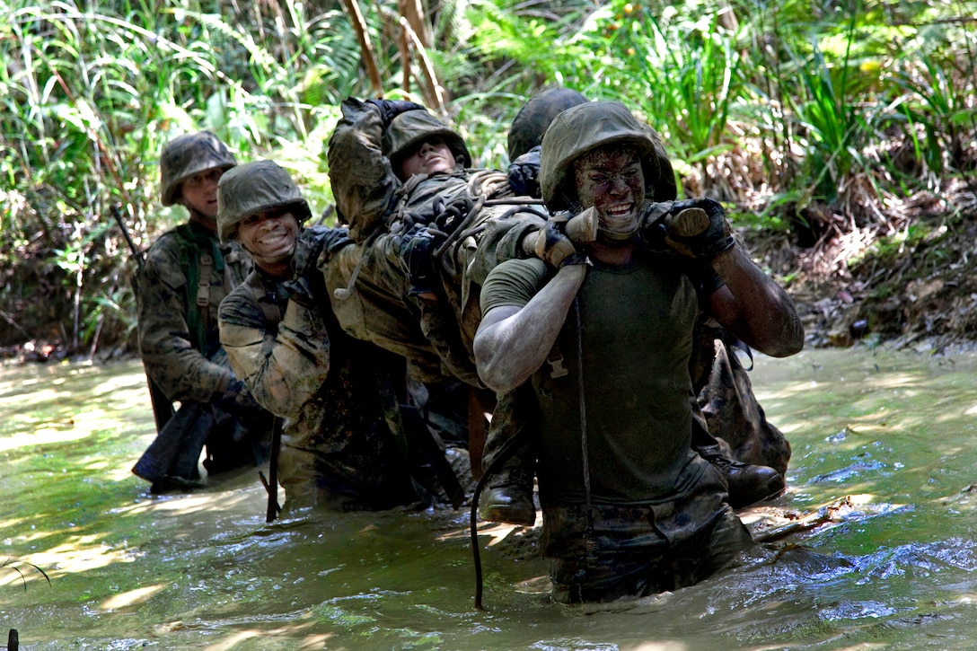 U.S. Marines carry an exercise participant simulating fatal injury through the water as they participate in the endurance course at the Jungle Warfare Training Center at Camp Gonsalves, Okinawa, Japan, April 29, 2011.