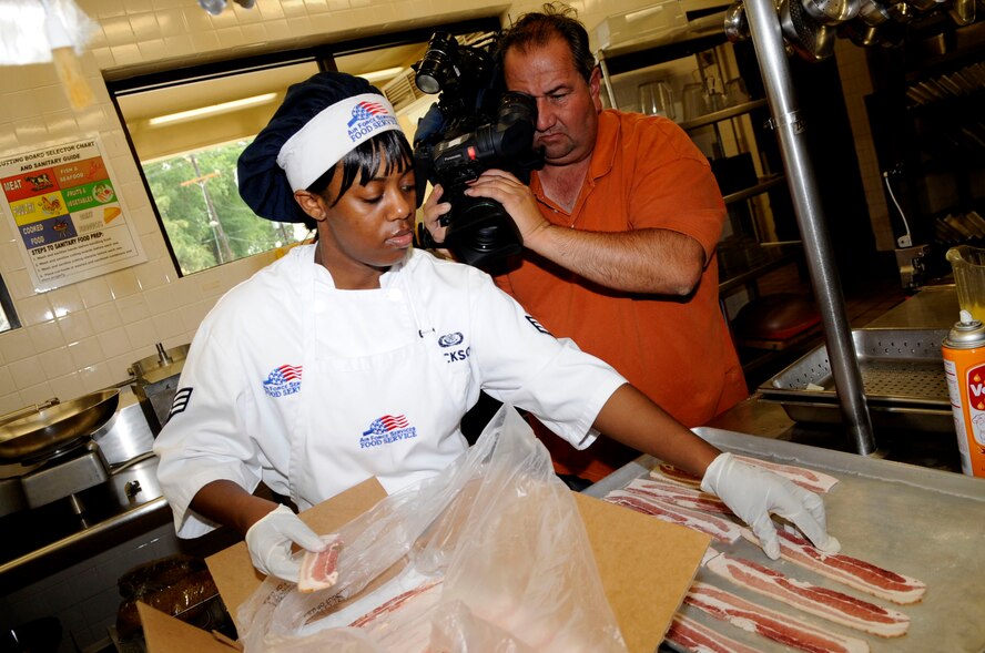 Art Nerio, a videographer from local Shreveport broadcast station KTAL 6, films Senior Airman Cornelia Jackson, 2nd Force Support Squadron, as she prepares lunch in the Red River Dining Facility on Barksdale Air Force Base, La., May 10. The story will air May 12 as part of the network’s year long spotlight on Barksdale. (U.S. Air Force photo/Staff Sgt. Terri Barriere)