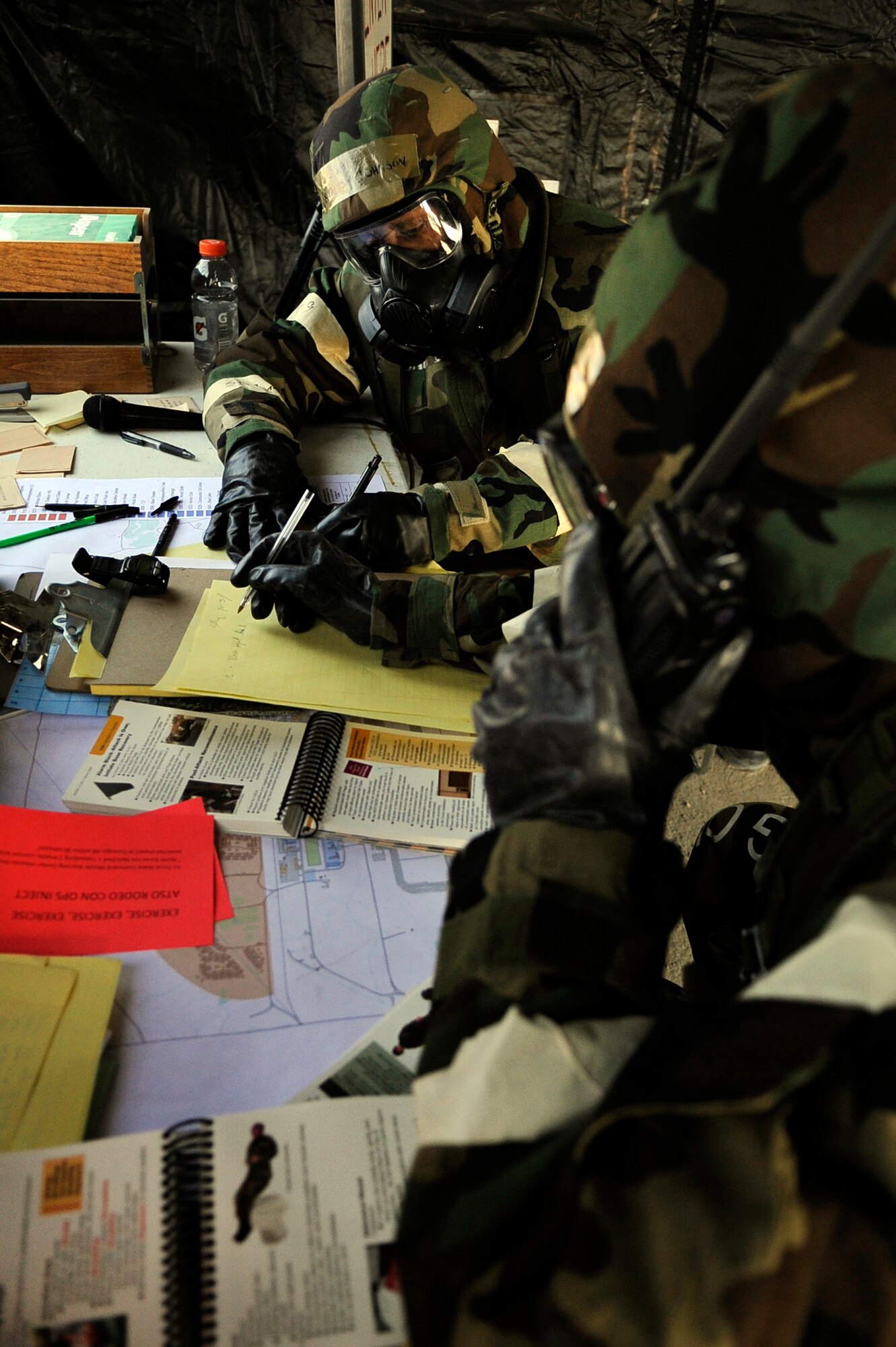 Top to Bottom: Cols. Karlton Johnson and Phillip Hoover work diligently at "Base X" during an operational readiness exercise evaluation May 5, 2011, Eielson Air Force Base, Alaska. The evaluation tests Airmen's ability to survive and operate in a simulated chemical, biological, radiological, nuclear, and high yield explosive environment.  The ORE provided Airmen with more command and control situations and improved scenarios. Colonel Johnson is the 354th Mission Support Group commander- and Colonel Hoover is the 354th Operation Group commander. (U.S. Air Force photo/Airman 1st Class Laura Goodgame) 