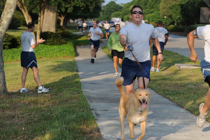 Staff Sgt. Jeff Curtain runs towards the finish line with his dog at the Commander's Fitness Challenge on Joint Base Charleston, May 9. May is fitness month and several base agencies came out to show their support by giving away free healthy snacks and other items. Additionally, the fastest male, female and overall runners were awarded commissary gift certificates. The commander's challenge course is approximately three miles long. Sergeant Curtain is a broadcaster assigned to the 1st Combat Camera Squadron. (U.S. Air Force photo/Staff Sgt. Nicle Mickle)