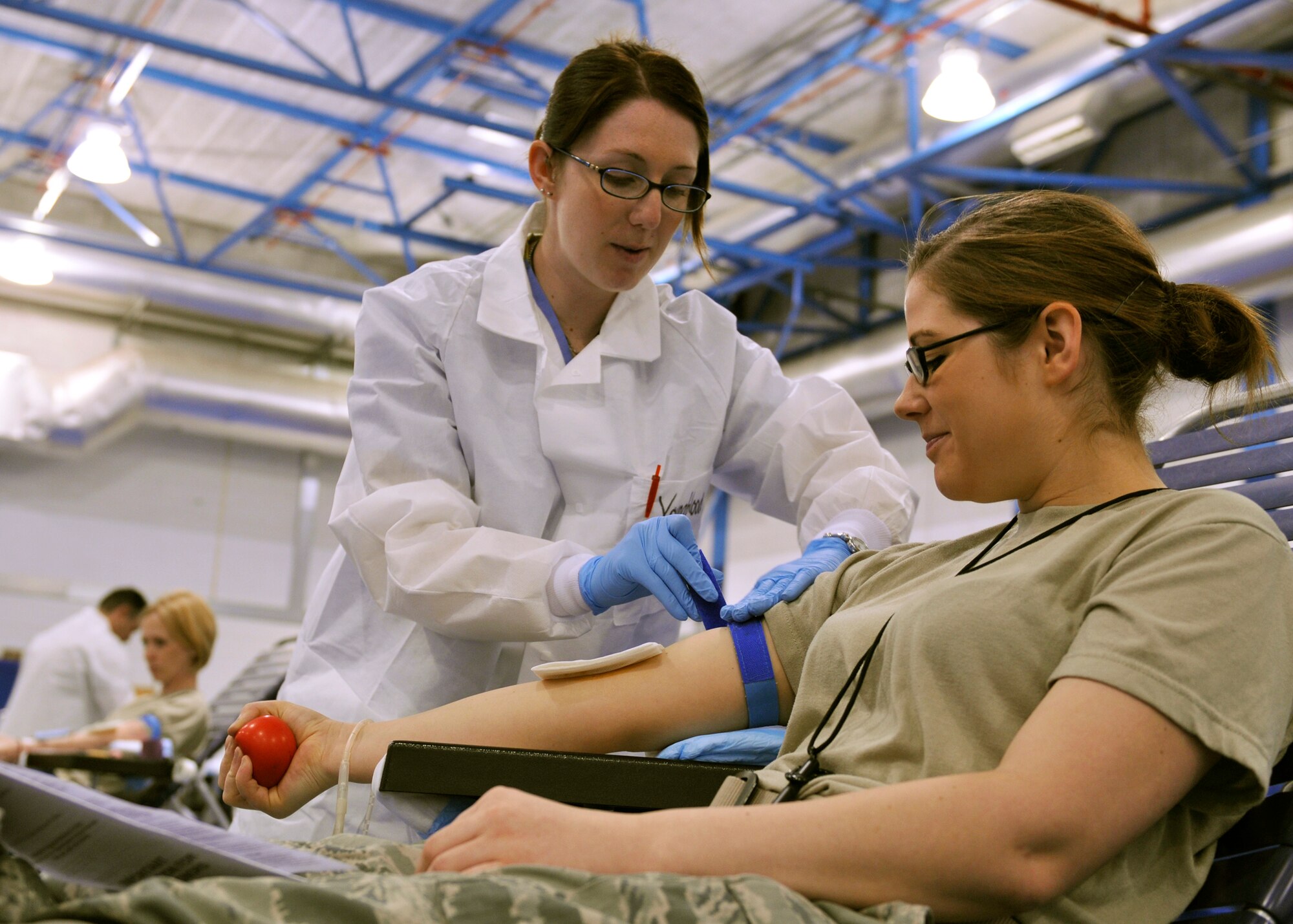 ROYAL AIR FORCE LAKENHEATH, England - Heather Youngblood, a phlebotomist from Landstuhl Regional Medical Center, Germany, tightens a strap on the arm of Airman 1st Class Elizabeth Dildy, 48th Aerospace Medical Squadron Bioenvironmental Engineering technician, during the Armed Services Blood Drive - Europe at the fitness center on May 10, 2011. (U.S. Air Force photo/Senior Airman Tiffany M. Deuel)