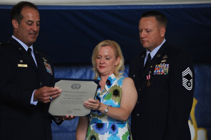 Col. Robert Holba presents Mrs. Heidi Tingelhoff a letter of appreciation while Chief Master Sgt. Rudy Tingelhoff watches during his retirement ceremony on Joint Base Charleston, May 6. Chief Tingelhoff served more than 29 years on active duty.  He entered the Air Force in September 1982 and worked in the security police career field and later cross-trained into the weather forecaster career field. Chief Tingelhoff retired as the 437th Operations Group superintendent. Colonel Holba is the 437 OG commander.  (U.S. Air Force photo/ Staff Sgt. Nicole Mickle) 