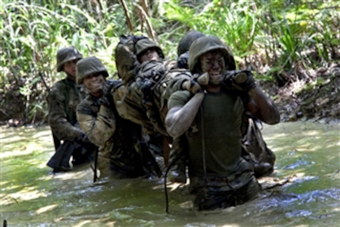 U.S. Marines carry an exercise participant simulating injury through the water as they participate in the endurance course at the Jungle Warfare Training Center at Camp Gonsalves, Okinawa, Japan, on April 29, 2011.  