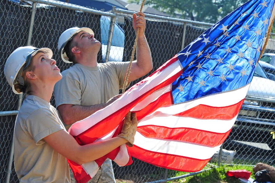 Airman Emily Meyer and Staff Sgt. Jared Smither, both from 2nd Communications Squadron, raise the American Flag to the top of a communications tower on Barksdale Air Force Base, La., May 6. Capt. Keith Lorenz administered the Oath of Enlistment to Senior Airman John Hines at 149 feet as part of a reenlistment ceremony. (U.S. Air Force photo/Senior Airman Joanna M. Kresge)
