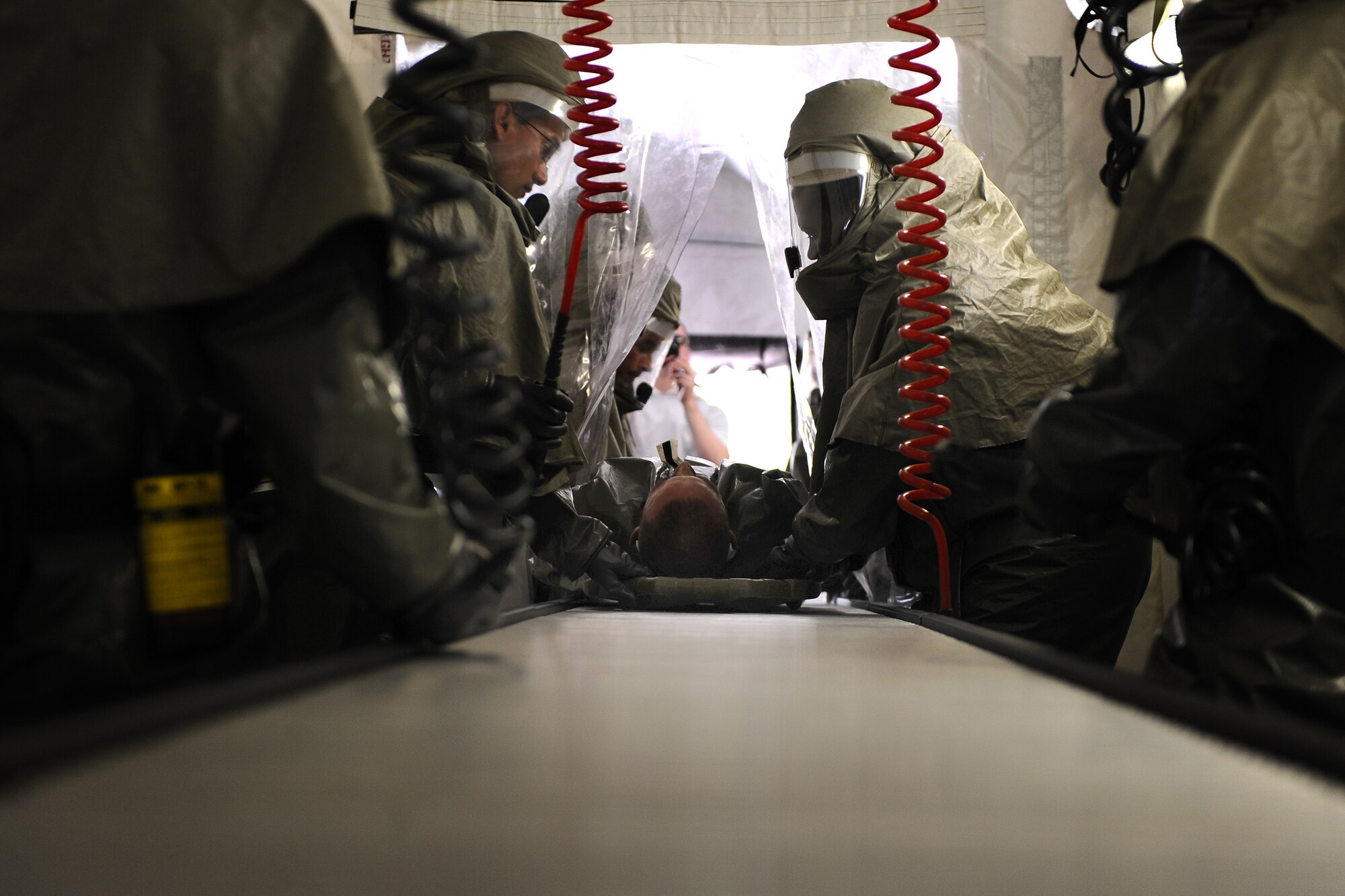 OFFUTT AIR FORCE BASE, Neb. - 55th Medical Group Airmen move a simulated contamination patient through the ambulatory line inside of the decontamination tent located at the McCoy Hall parking lot, here, May 10.  Frequent training ensures the medical professionals are capable of moving people efficiently through the decontamination tent.  The ambulatory line is a section of the DECON tent where immobilized patients are pushed though the rollers while laying on a stretcher. U.S. Air Force Photo by Josh Plueger (released)
