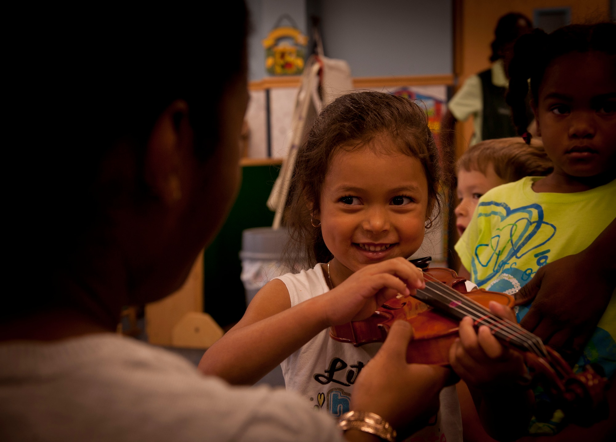 Bryanna Case, daughter of Staff Sgt. Barbra Case, 23rd Logistics Readiness Squadron vehicle management analysis, is shown how to strum violin strings May 9 at Moody Air Force Base, Ga. Jovan DeShong, Valdosta State University music education major, visited Moody to teach children at the Child Development Center how to play the instrument. (U.S. Air Force photo/ Airman 1st Class Joshua Green)(RELEASED)
