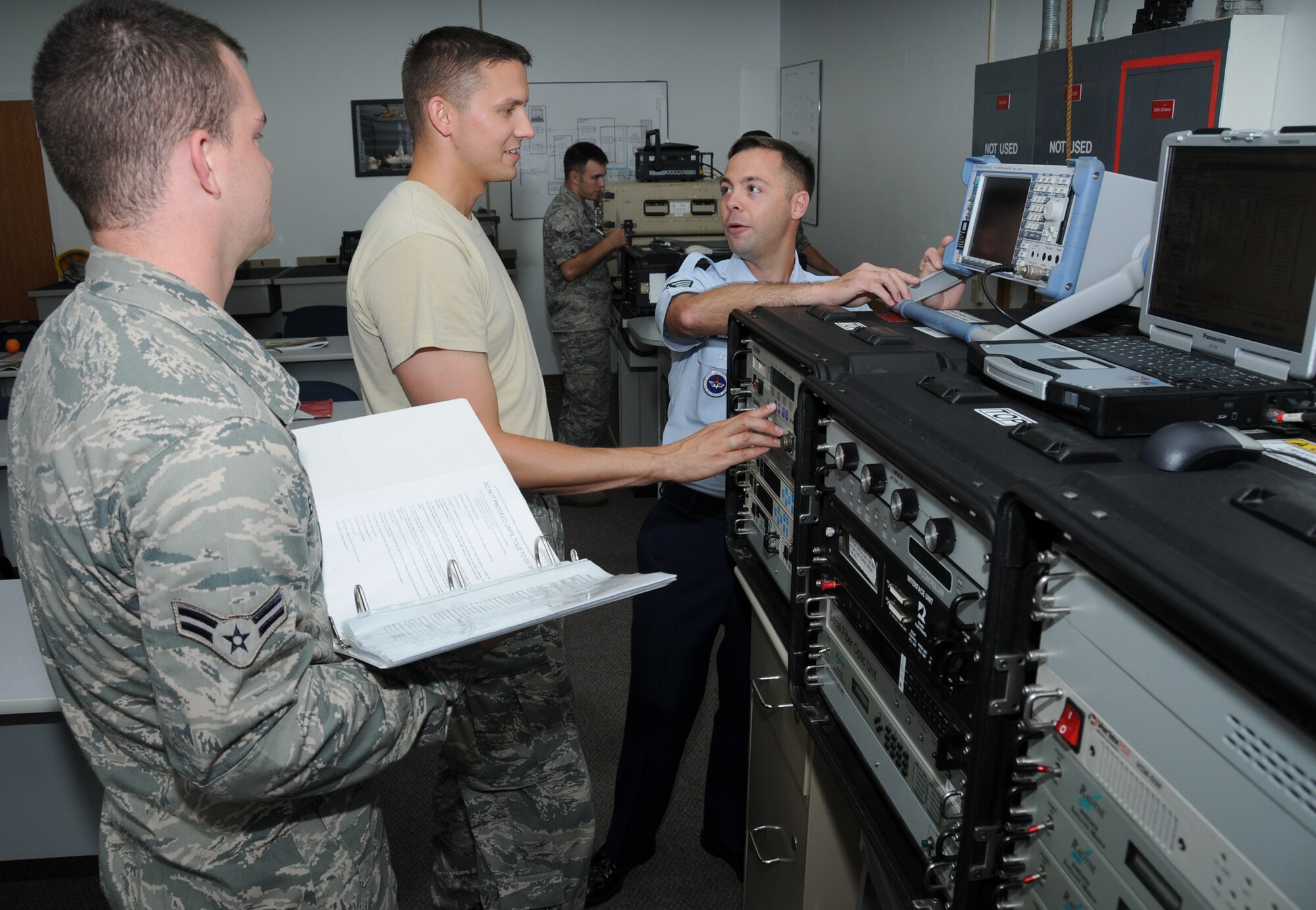 From left, Airmen 1st Class Kenneth Fleck and Nicholas Boudreau, students in the 338th Training Squadron's radio frequency transmission course, and their instructor, Tech. Sgt. Tony Barattini, go through the steps for using tactical satellite communications with their distant end in order to establish data transfer in a Jones Hall classroom Monday.  (U.S. Air Force photo by Kemberly Groue)

