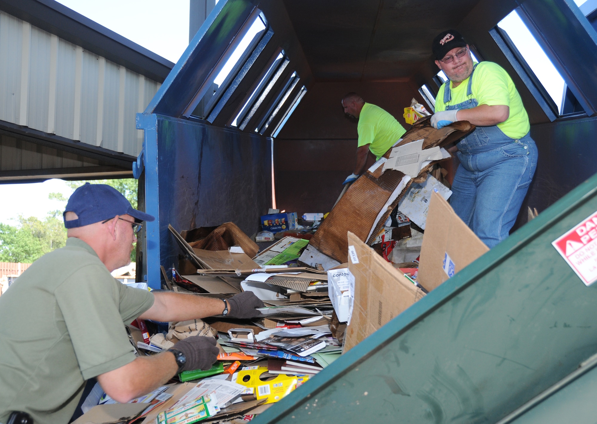 From left, Mr. Robertson, Duane Olson and Douglas Houle work to empty a cardboard recycling bin to prepare the cardboard for binding into bales. Zero Waste Solutions collects a variety of recyclables and sells it to local processing companies.
Proceeds collected from the sale is given back to the government.   (U.S. Air Force photo by Kemberly Groue)