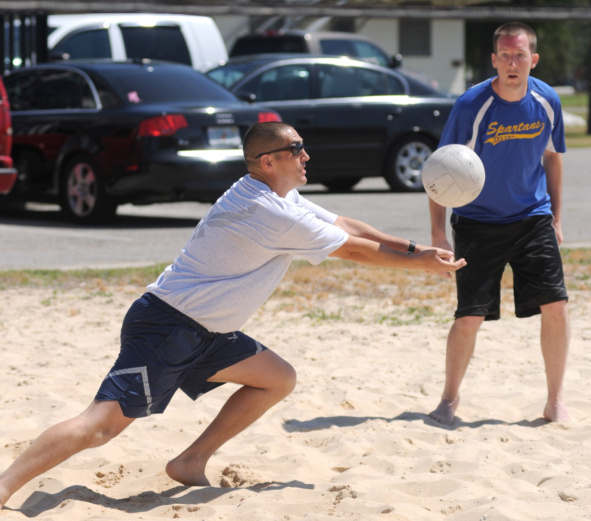 Joel Shepherd stretches to bump the ball while teammate Josh Fuqua stands by during a sand volleyball match during Sports Day, May 5.  They are assigned to the 333rd Training Squadron.   (U.S. Air Force photo by Kemberly Groue)