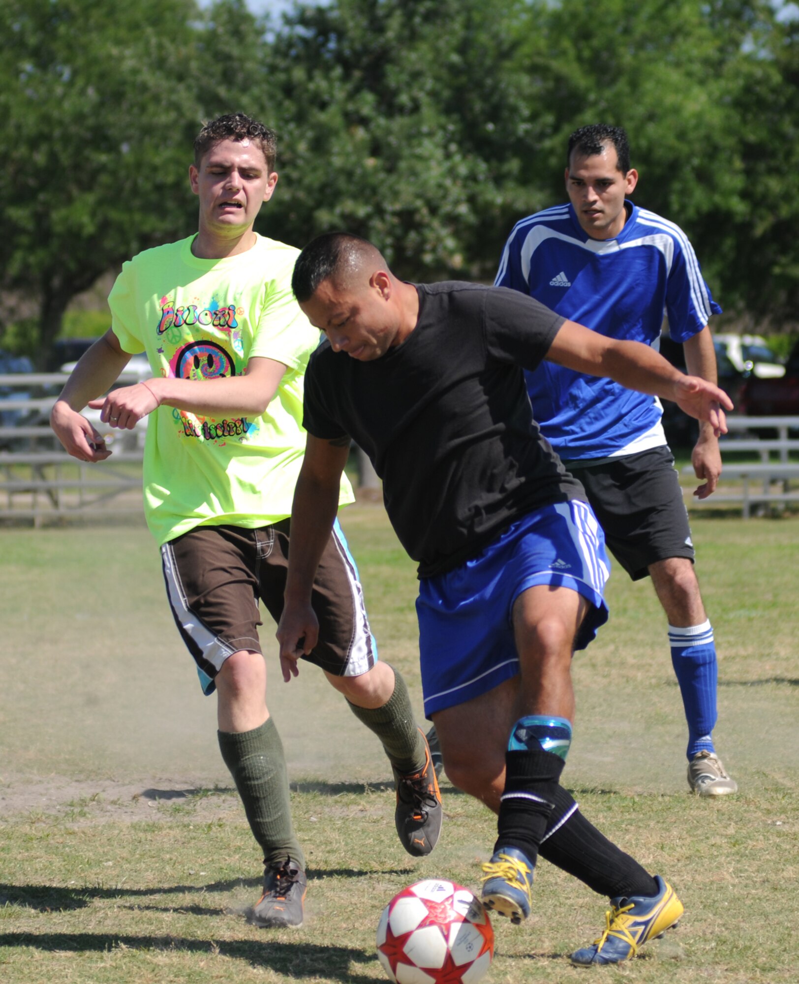 Jake Broersma, 81st Dental Squadron, dribbles the ball past defender Jason  Syverson, left, 81st Inpatient Operations Squadron intensive care unit, as he makes his way toward the goal during a three-on-three soccer match at Meadows Field. Teammate Aaron Betancourt, 81st DS, positions himself on the field of play.   (U.S. Air Force photo by Kemberly Groue)