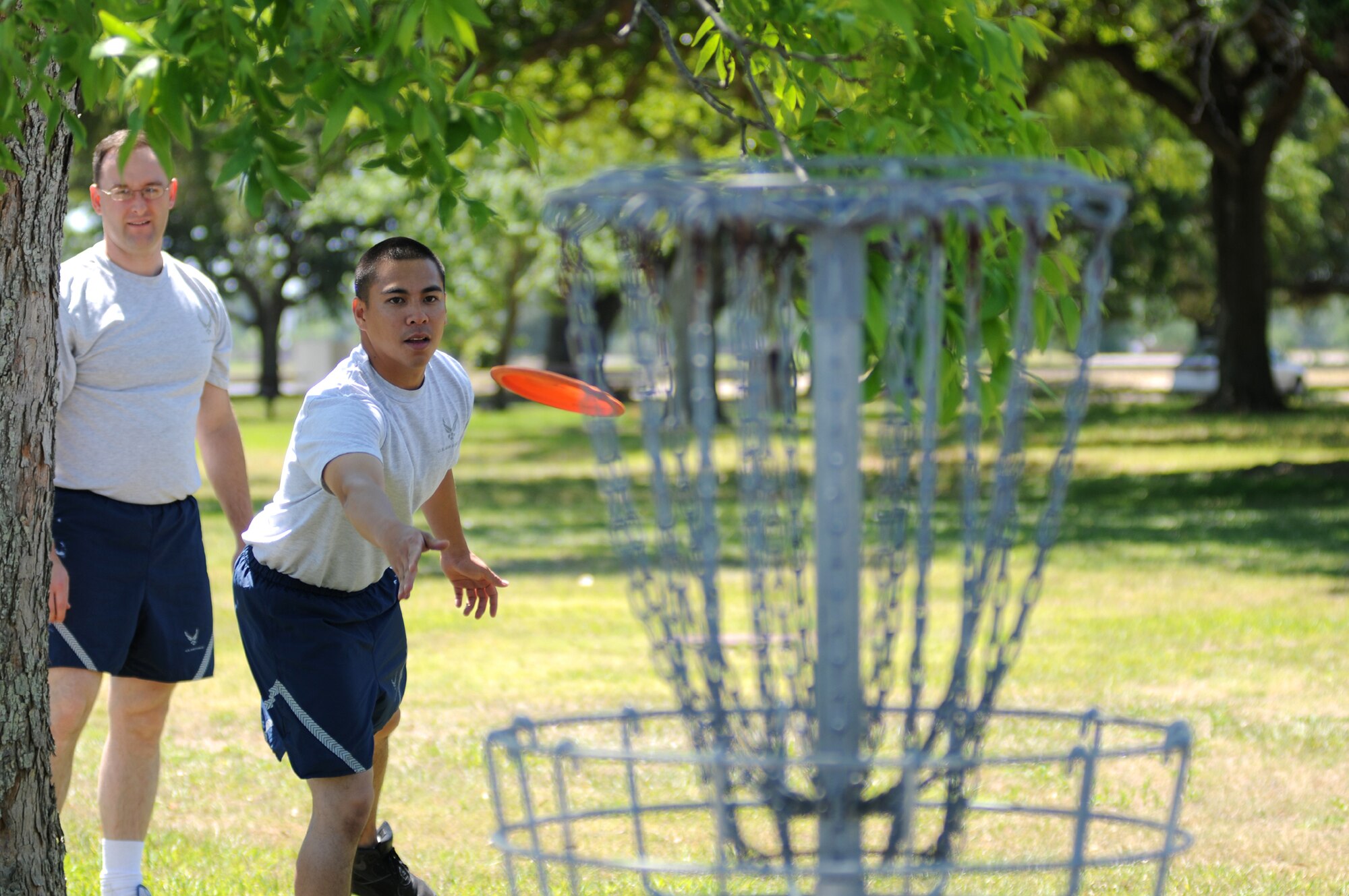Lester Naoe, 81st TRSS, places just the right spin on the frisbee as he tries to toss
it into the chain-link basket during a game of frisbee golf. Karl Knowlton, 81st TRSS, looks on as he waits his turn.   (U.S. Air Force photo by Kemberly Groue)