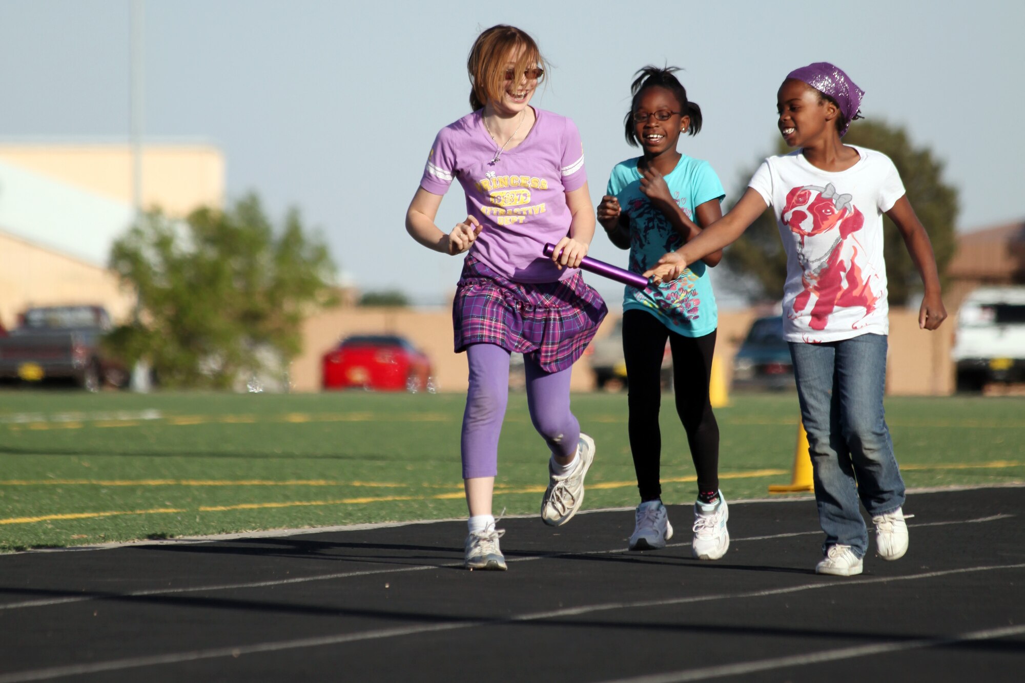 Children from the Youth Center pass the baton while learning how to run a relay race during a track and field clinic at the Cannon Air Force Base track, May 4-5, 2011.  During this clinic they were taught the different sports available in track such as throwing shot put and sprinting in races. (by Airman 1st Class Jette Carr)(RELEASED)