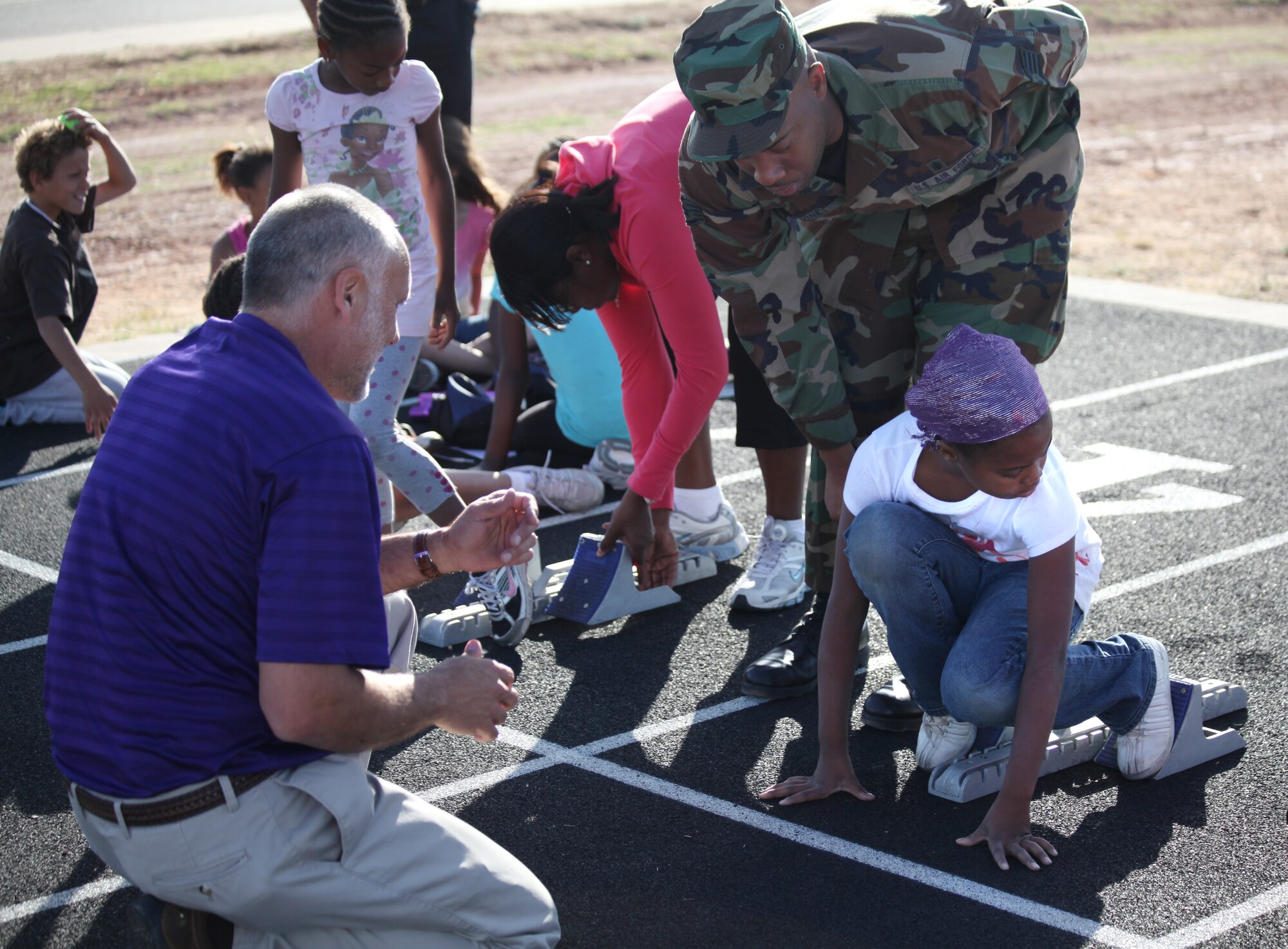 Brian Stacy, the athletic director for Clovis Municipal Schools, and Staff Sgt. Carlton Jones, medical technician, 27th Special Operations Maintenance Operations Squadron, help Sergeant Jones' daughter Jordan line-up on the starting block at Cannon Air Force Base N.M. track May 5, 2011. Jordan and other youth participated in a track and field clinic, May 4-5, 2011, where they learned different aspects of running such as correct form, warm-up, and the different types of races.  (by Airman 1st Class Jette Carr)(RELEASED)