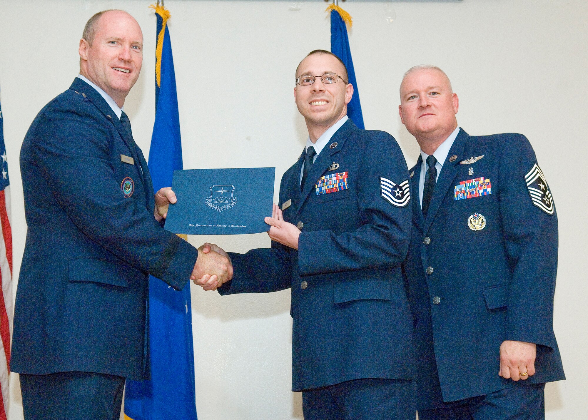 Edwards Community College of the Air Force graduate, Tech. Sgt. Eric Smith (center) , is presented his diploma by Brig. Gen. Robert C. Nolan II, Air Force Flight Test Center commander, and Chief Master Sgt. Bill Thomaston, 95th Air Base Wing command chief, at Club Muroc, May 5. (Air Force photo by Rob Densmore)