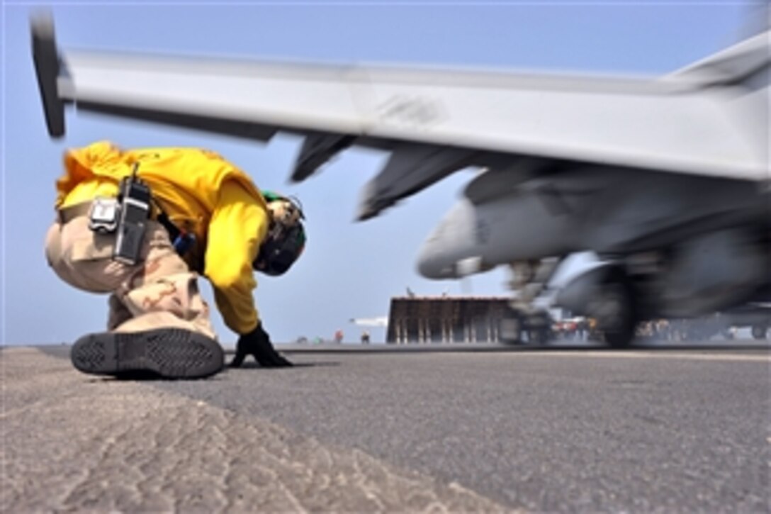 Lt. Mark D. Kurtz, an aircraft shooter, takes cover from jet blast as he launches an F/A-18F Super Hornet assigned to Strike Fighter Squadron 211 aboard the aircraft carrier USS Enterprise (CVN 65) in the Arabian Sea on May 9, 2011.  The Enterprise and Carrier Air Wing 1 are conducting close-air support missions as part of Operation Enduring Freedom in the U.S. 5th Fleet area of responsibility.  