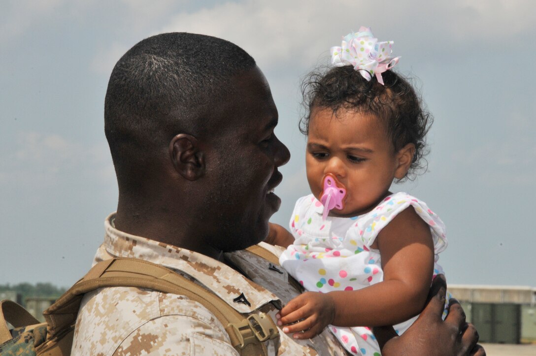 Lance Cpl. Mitchell T. Spead Jr., VMR BC Det crew chief, holds one of his young daughters after arriving home from a three-month deployment to Al Udeid Air Base, Qatar.   (US Navy Photos by Tammy Prine/Released)